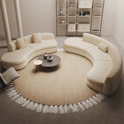 Modern living room with curved beige sofa, round rug, and decorative items.